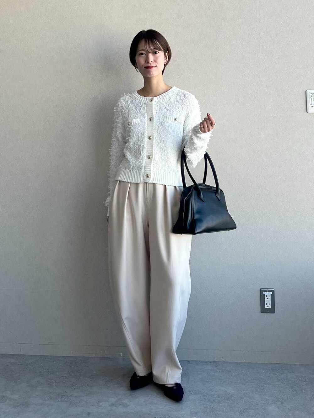 ブラック系のトートバッグ、ホワイト系のカーディガン/ボレロ、ブラック系のパンプスを着用したレディースの冬コーディネートの4枚目の写真