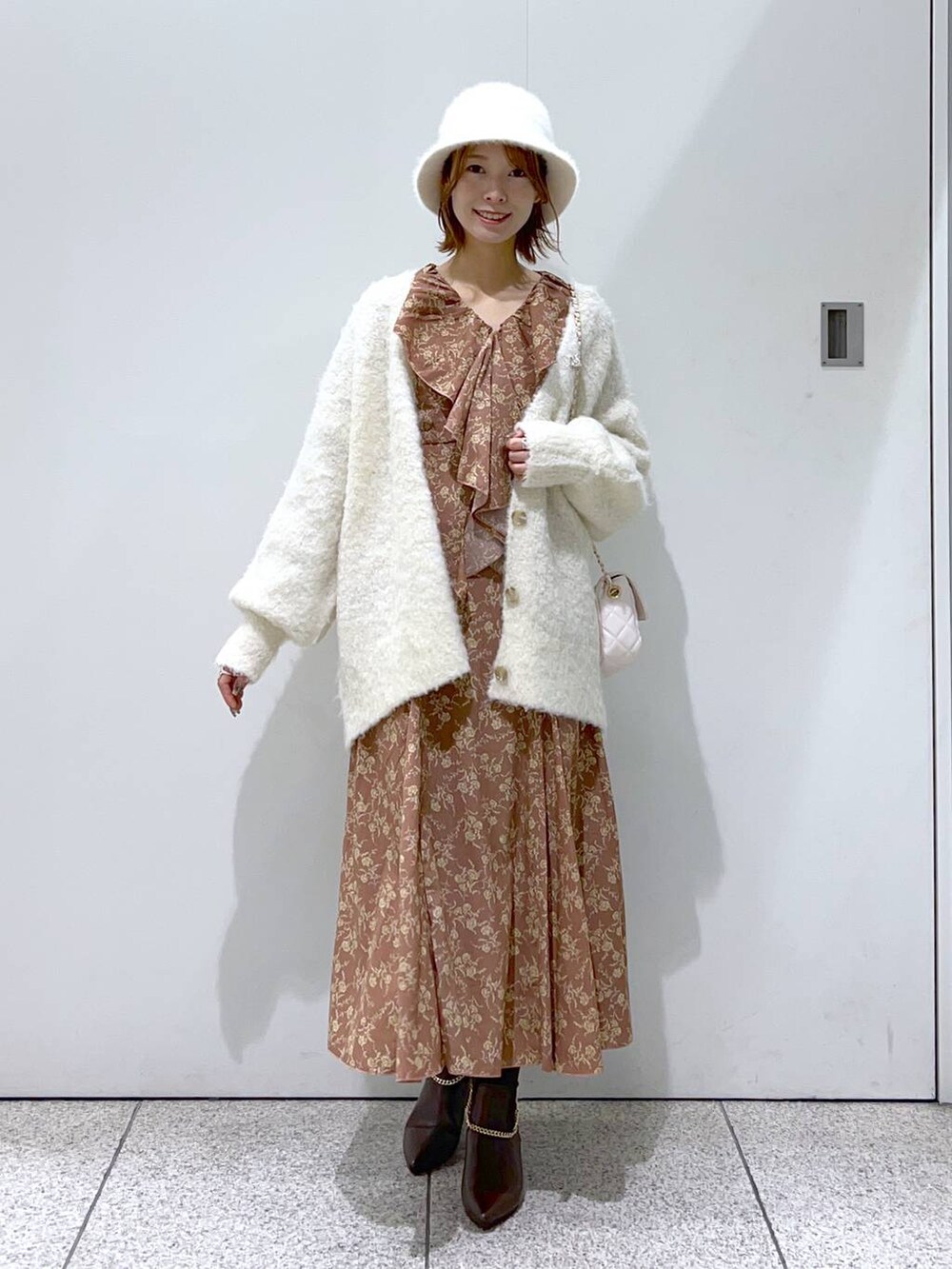 ホワイト系のショルダーバッグ、ホワイト系のカーディガン/ボレロ、ブラウン系のブーツを着用したレディースの秋コーディネートの2枚目の写真