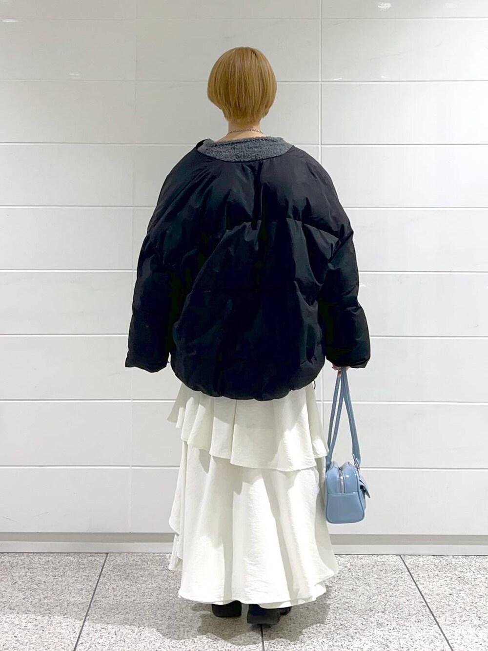 ブラック系のブーツ、ホワイト系のスカート、ブラック系のブルゾンを着用したレディースの冬コーディネートの3枚目の写真