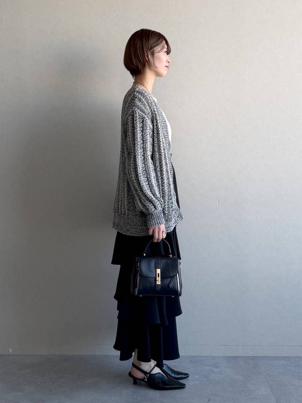 ブラック系のショルダーバッグ、ブラック系のサンダル、ホワイト系のニット/セーターを着用したレディースの冬コーディネートの2枚目の写真