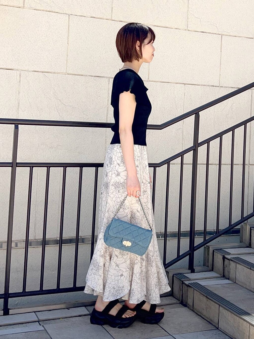 ブラック系のニット/セーター、ブルー系のショルダーバッグ、ホワイト系のスカートを着用したレディースの夏コーディネートの3枚目の写真