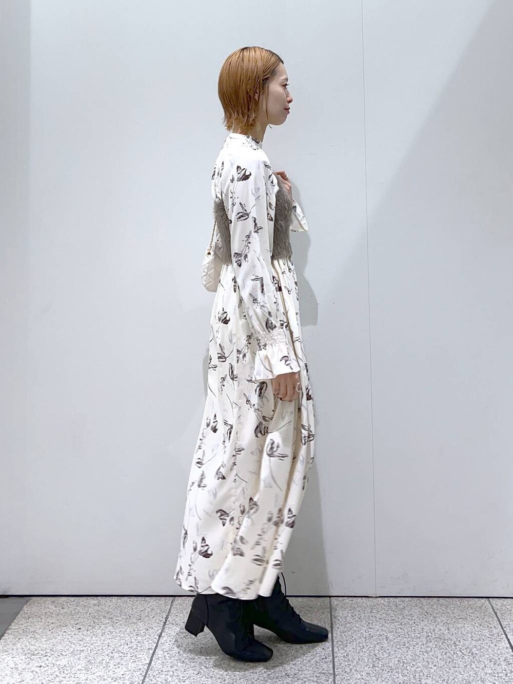 ホワイト系のショルダーバッグ、ブラック系のブーツ、ホワイト系のチェスターコートを着用したレディースの冬コーディネートの5枚目の写真