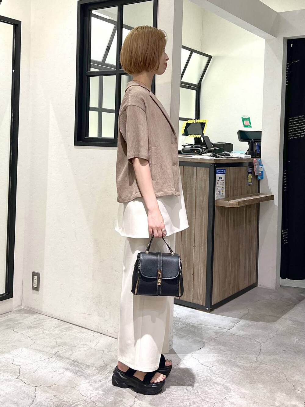 ブラック系のサンダル、ベージュ系のテーラードジャケット、ブラック系のショルダーバッグを着用したレディースの夏コーディネートの3枚目の写真