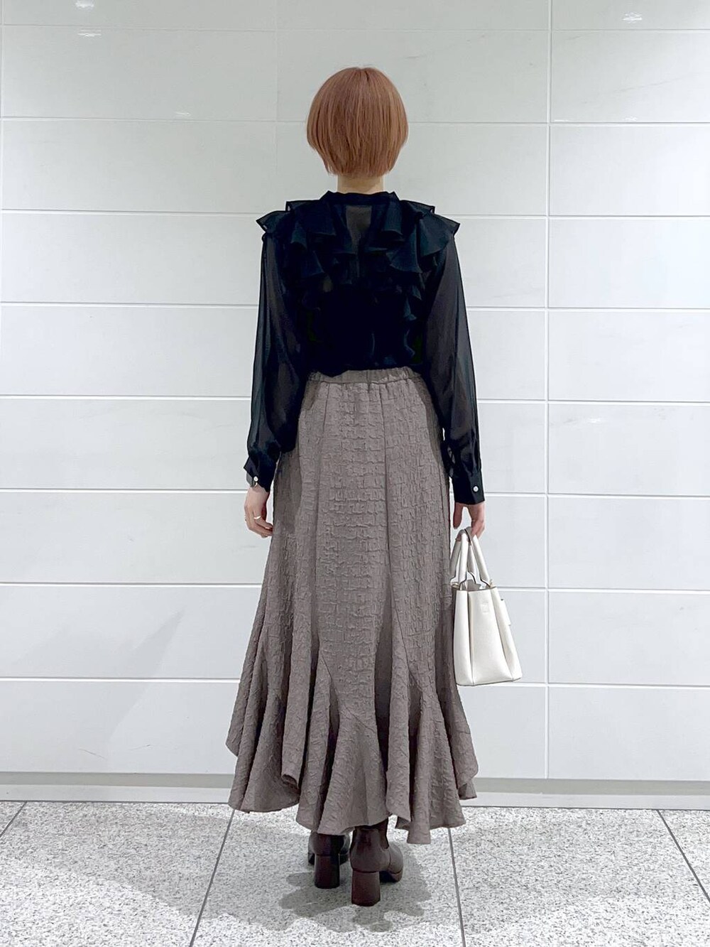 ブラウン系のブーツ、ホワイト系のショルダーバッグ、ブラック系のシャツ/ブラウスを着用したレディースの冬コーディネートの4枚目の写真