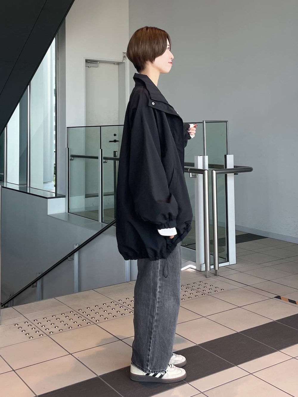 ブラウン系のボストンバッグ、ホワイト系のTシャツ/カットソー、ブラック系のブルゾンを着用したレディースの秋コーディネートの2枚目の写真