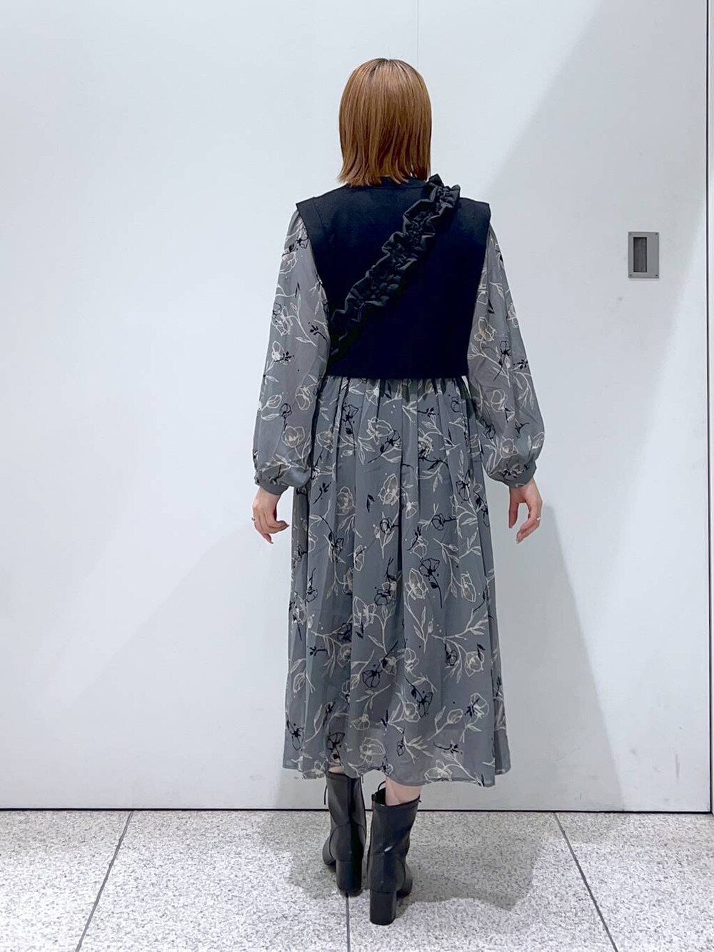 ブラック系のハンドバッグ、ブラック系のブーツ、グレー系のワンピースを着用したレディースの秋コーディネートの3枚目の写真