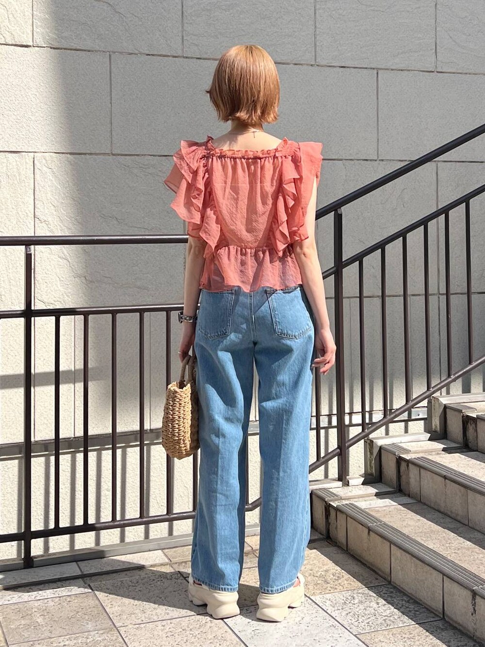 ブルー系のデニムパンツ、ホワイト系のサンダル、ピンク系のシャツ/ブラウスを着用したレディースの春コーディネートの3枚目の写真