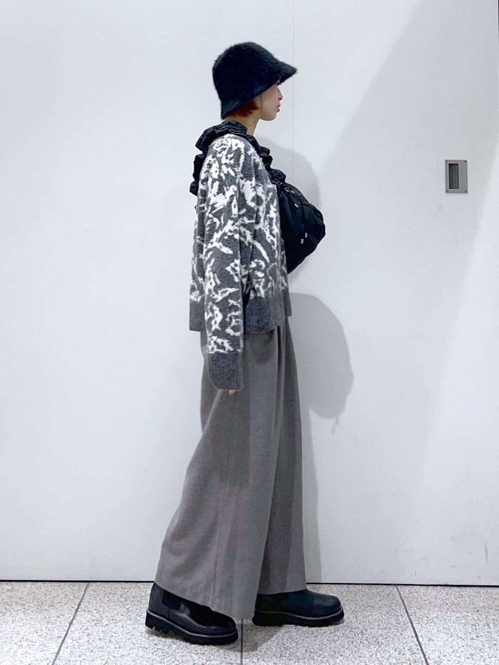 ブラック系のハンドバッグ、ブラック系のブーツ、グレー系のニット/セーターを着用したレディースの冬コーディネートの2枚目の写真