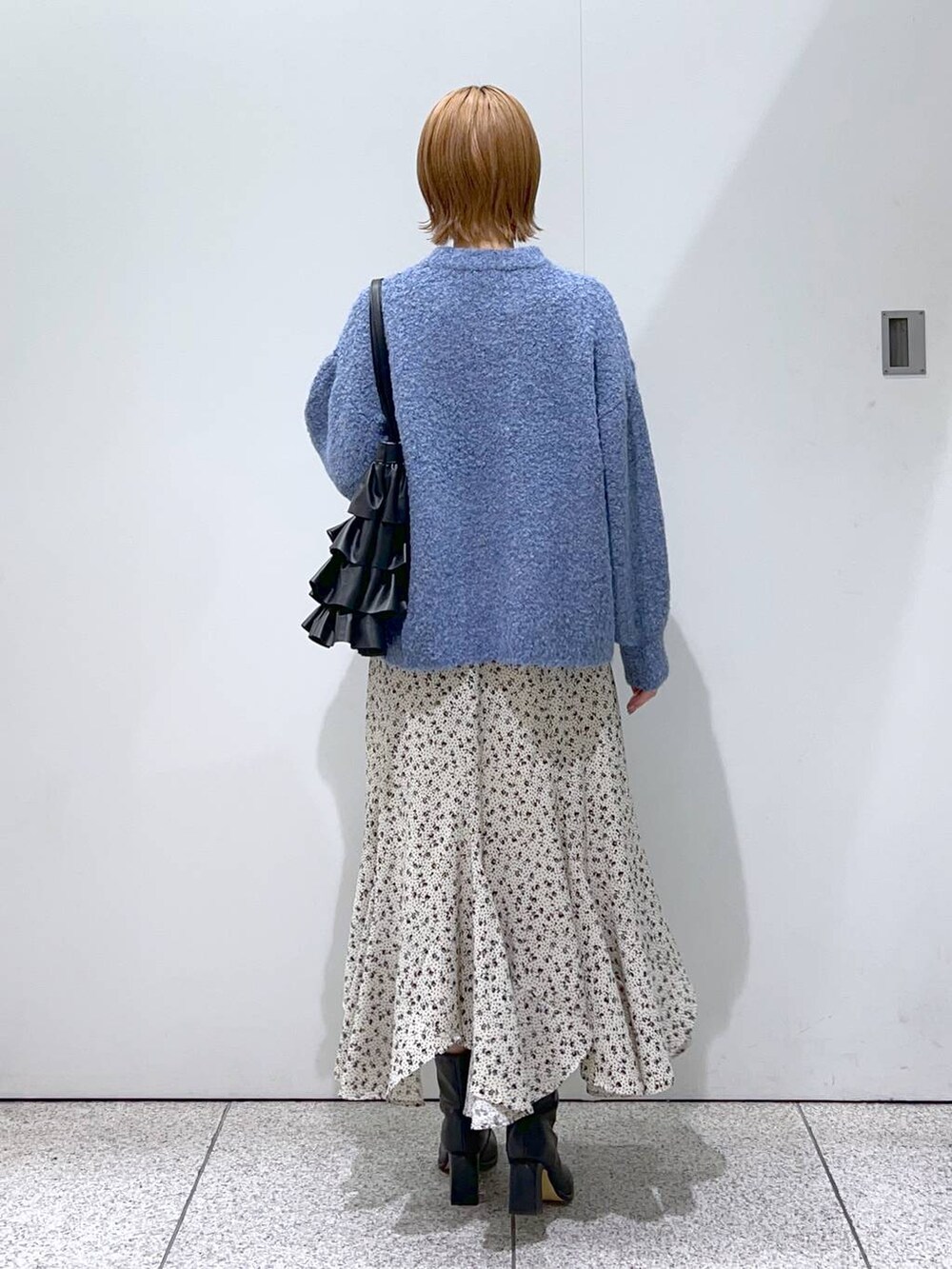 ブラック系のブーツ、ブルー系のニット/セーター、ホワイト系のスカートを着用したレディースの冬コーディネートの7枚目の写真