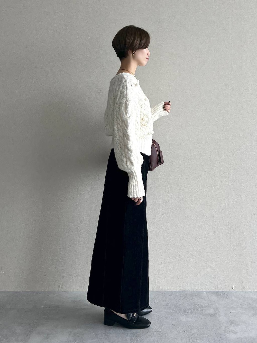 レッド系のハンドバッグ、ブラック系のスカート、ブラック系のローファーを着用したレディースの秋コーディネートの5枚目の写真