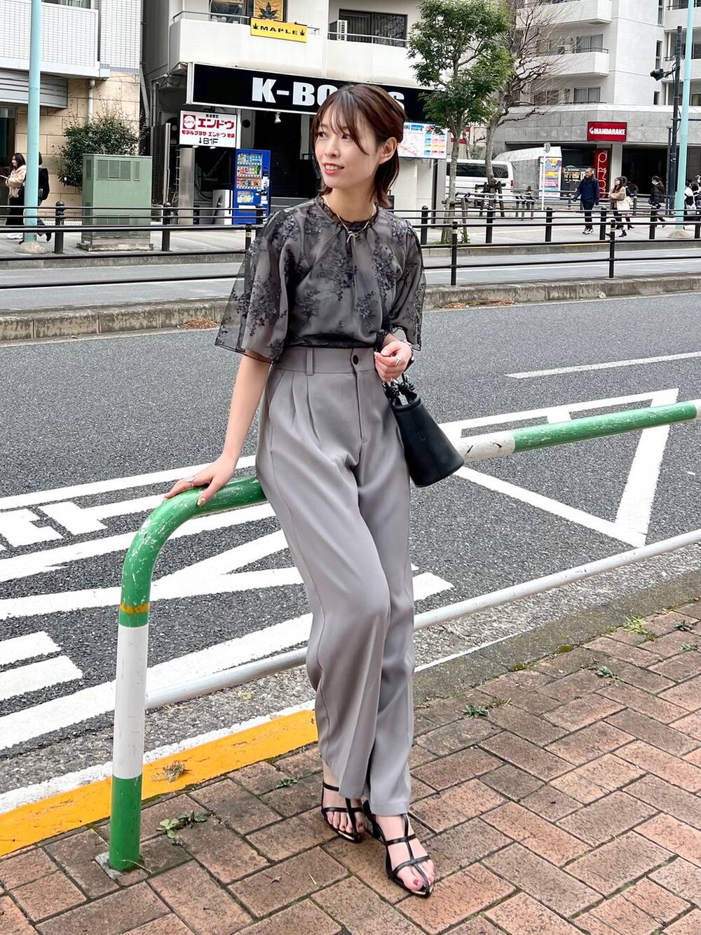 ブラック系のシャツ/ブラウス、ブラック系のサンダル、ブラック系のハンドバッグを着用したレディースの春コーディネートの6枚目の写真