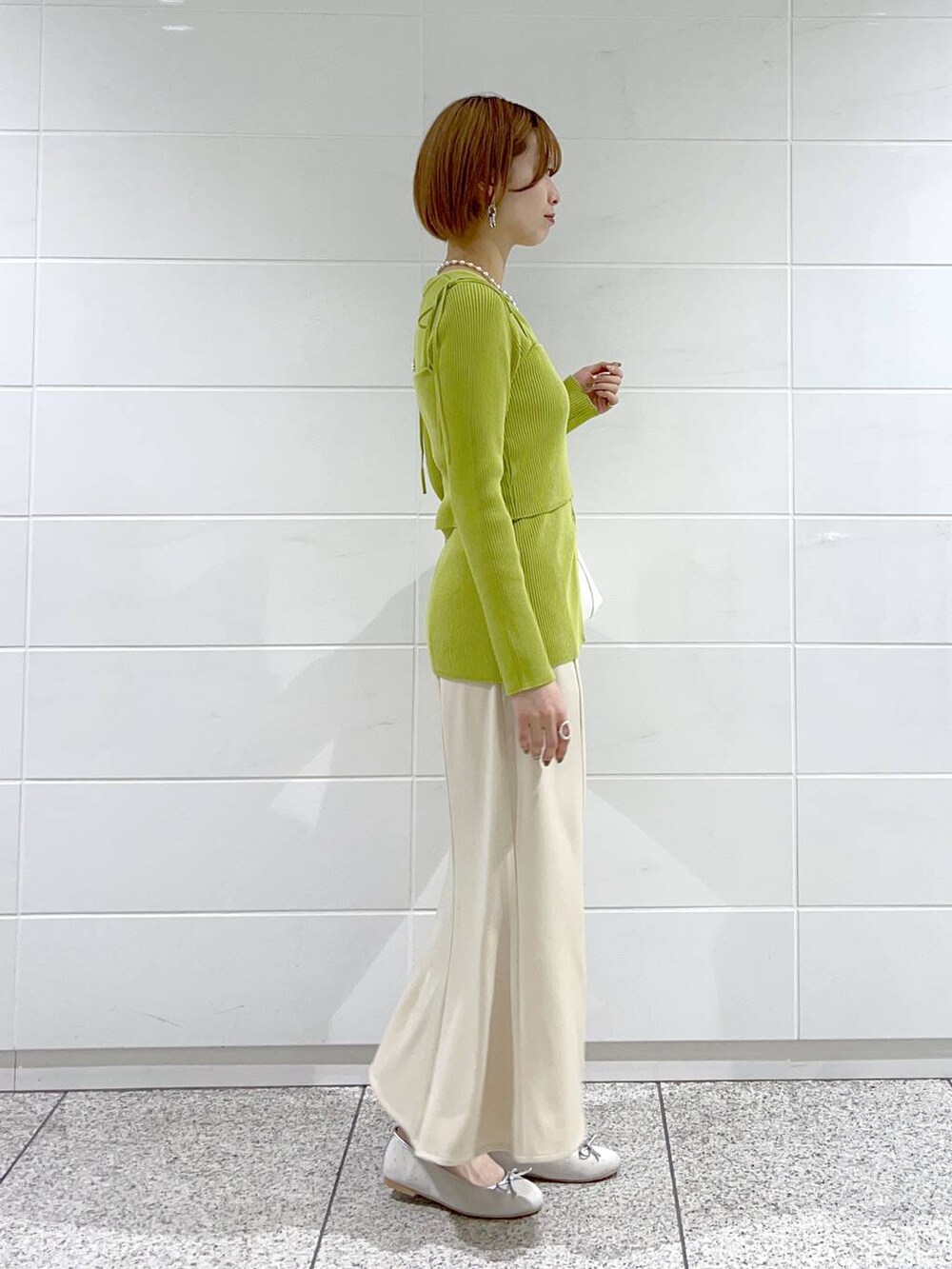 ベージュ系のスカート、シルバー系のバレエシューズ、グリーン系のカーディガン/ボレロを着用したレディースの春コーディネートの2枚目の写真