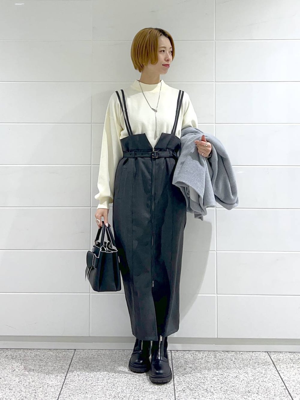 ブラック系のブーツ、ホワイト系のニット/セーター、ブラック系のショルダーバッグを着用したレディースの冬コーディネートの4枚目の写真