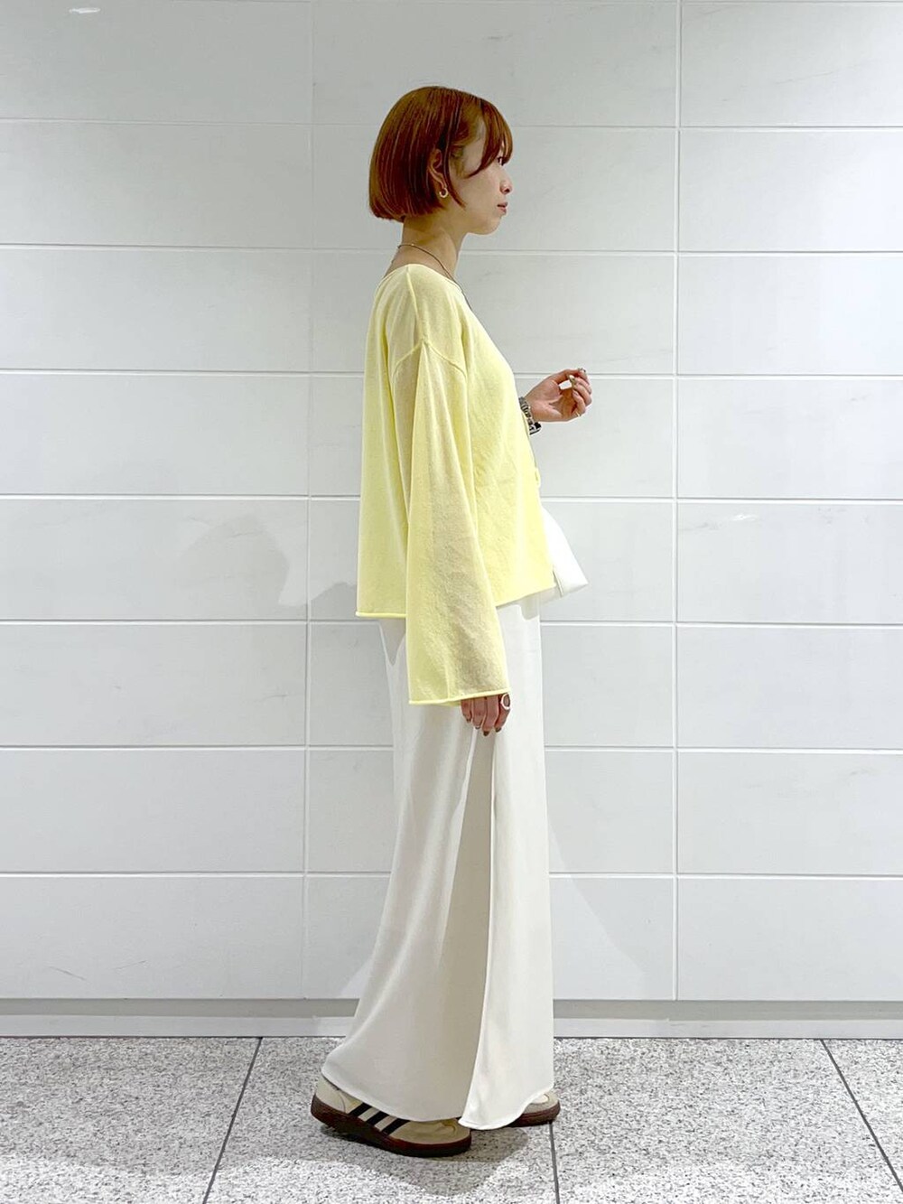 イエロー系のニット/セーター、グレー系のテーラードジャケット、ホワイト系のスカートを着用したレディースの春コーディネートの5枚目の写真