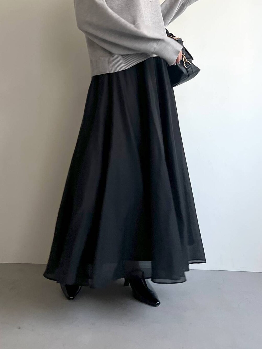 ブラック系のボストンバッグ、ブラック系のサンダル、グレー系のニット/セーターを着用したレディースの冬コーディネートの5枚目の写真