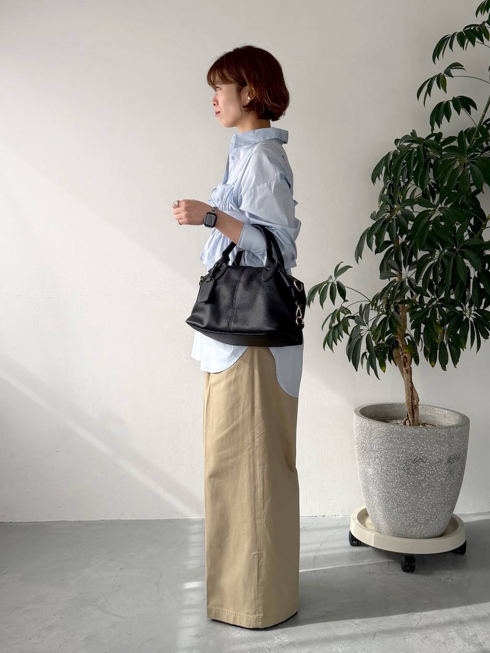 ブラック系のボストンバッグ、ブルー系のシャツ/ブラウス、ベージュ系のチノパンツを着用したレディースの春コーディネートの2枚目の写真
