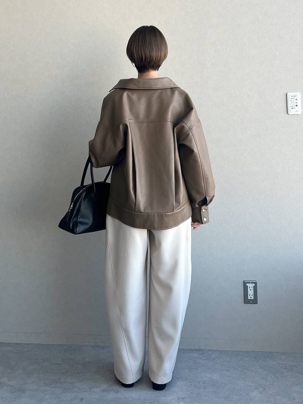 ブラック系のトートバッグ、ホワイト系のカーディガン/ボレロ、ブラック系のパンプスを着用したレディースの冬コーディネートの3枚目の写真