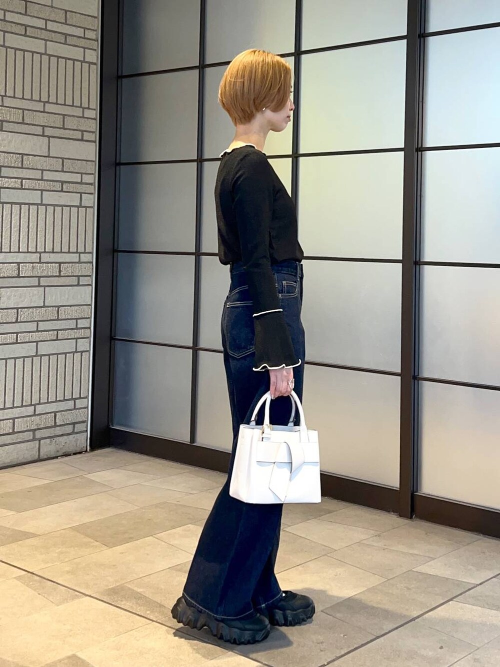 ホワイト系のブルゾン、ホワイト系のショルダーバッグ、ブルー系のスラックスを着用したレディースの冬コーディネートの5枚目の写真