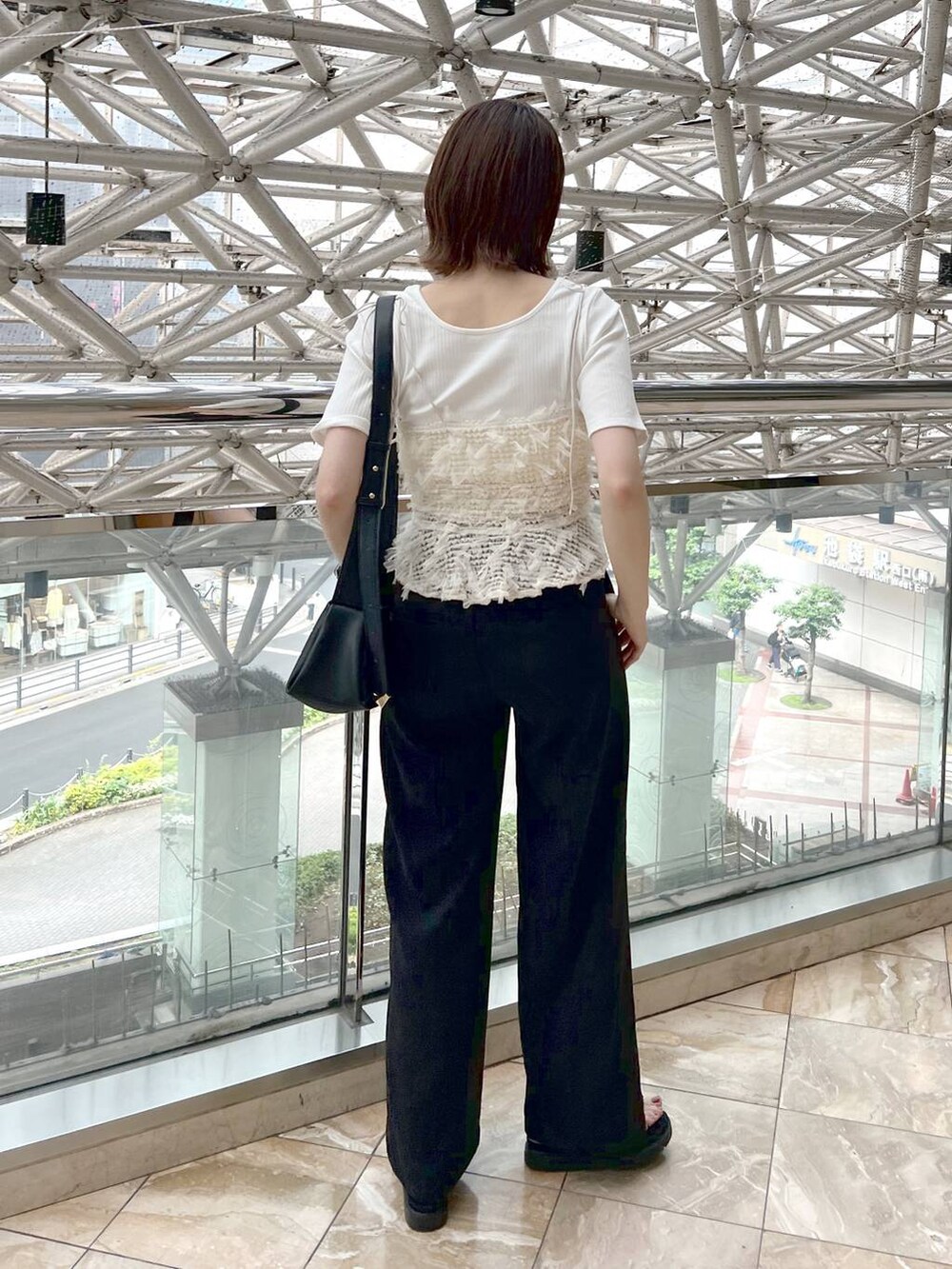 ブラック系のサンダル、ブラック系のスラックス、ブラック系のショルダーバッグを着用したレディースの春コーディネートの2枚目の写真