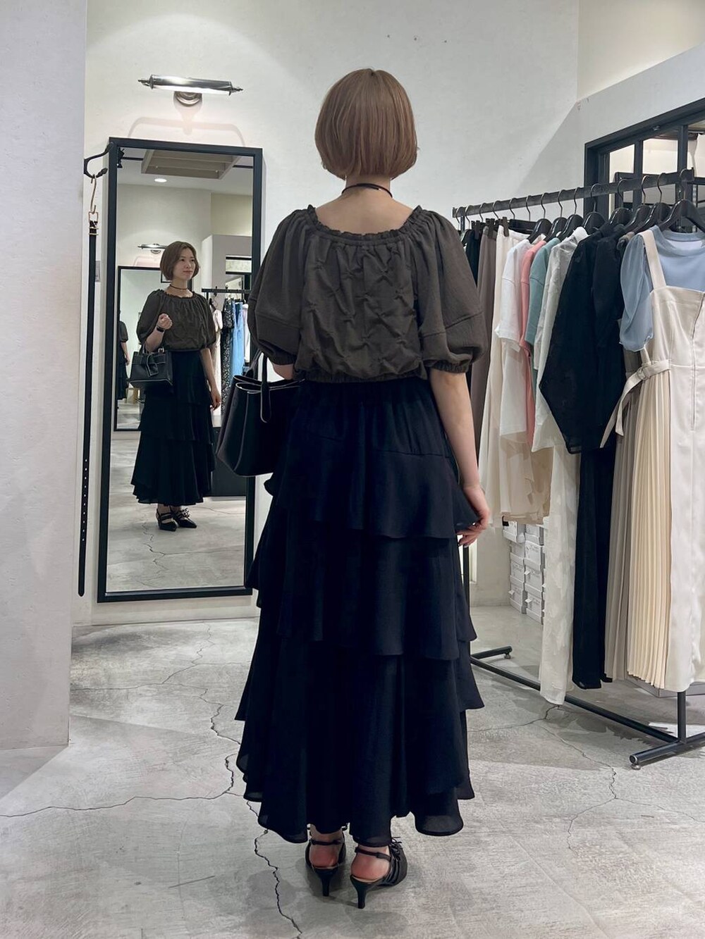 ブラック系のショルダーバッグ、ブラウン系のシャツ/ブラウス、ブラック系のスカートを着用したレディースの夏コーディネートの3枚目の写真