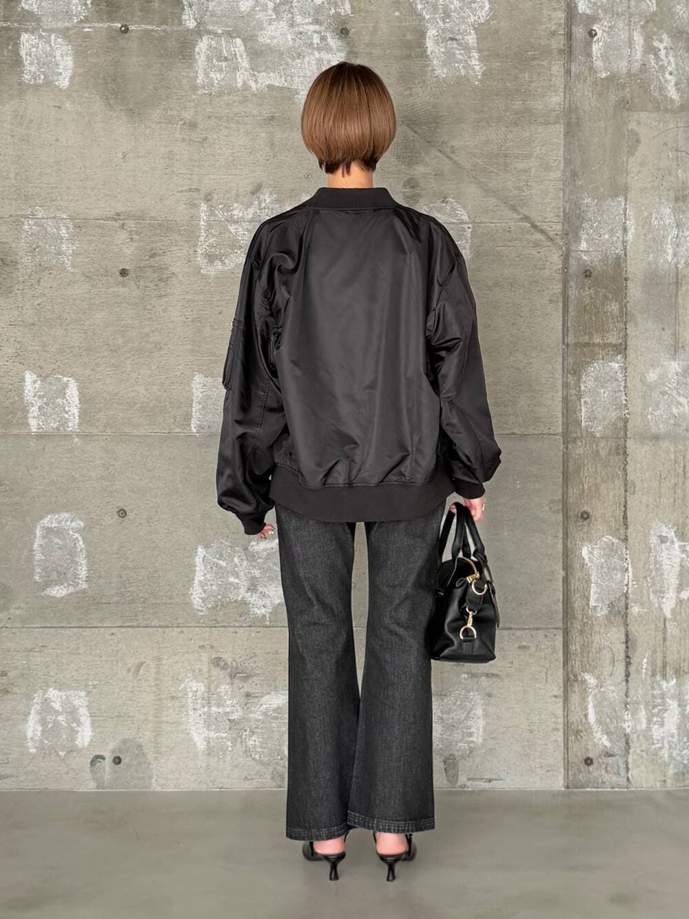 ブラック系のボストンバッグ、ブラック系のデニムパンツ、ブラック系のサンダルを着用したレディースの冬コーディネートの3枚目の写真