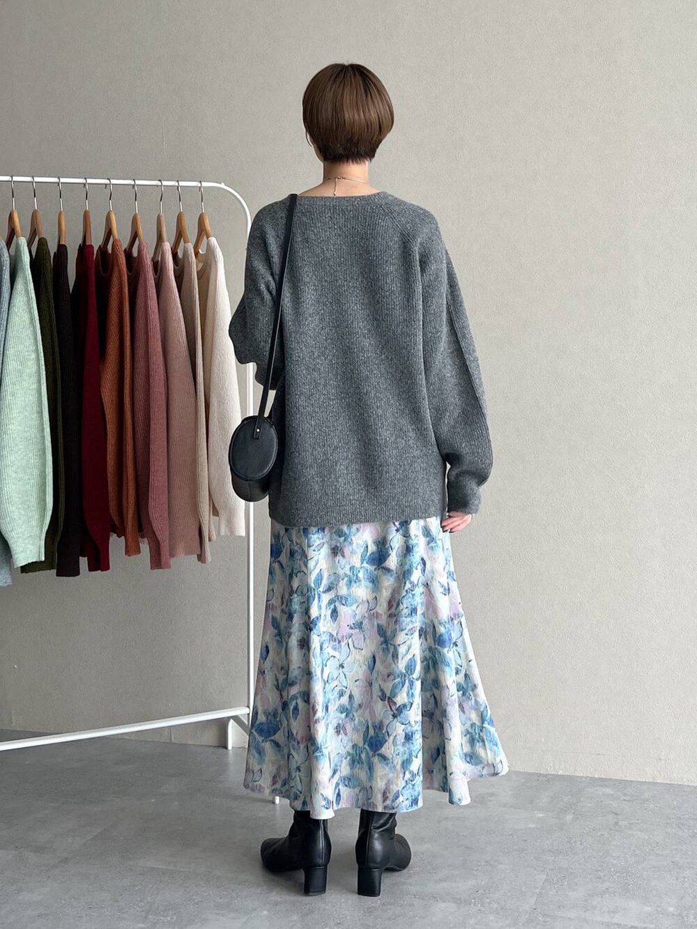 ホワイト系のスカート、ブラック系のショルダーバッグ、グレー系のニット/セーターを着用したレディースの秋コーディネートの3枚目の写真