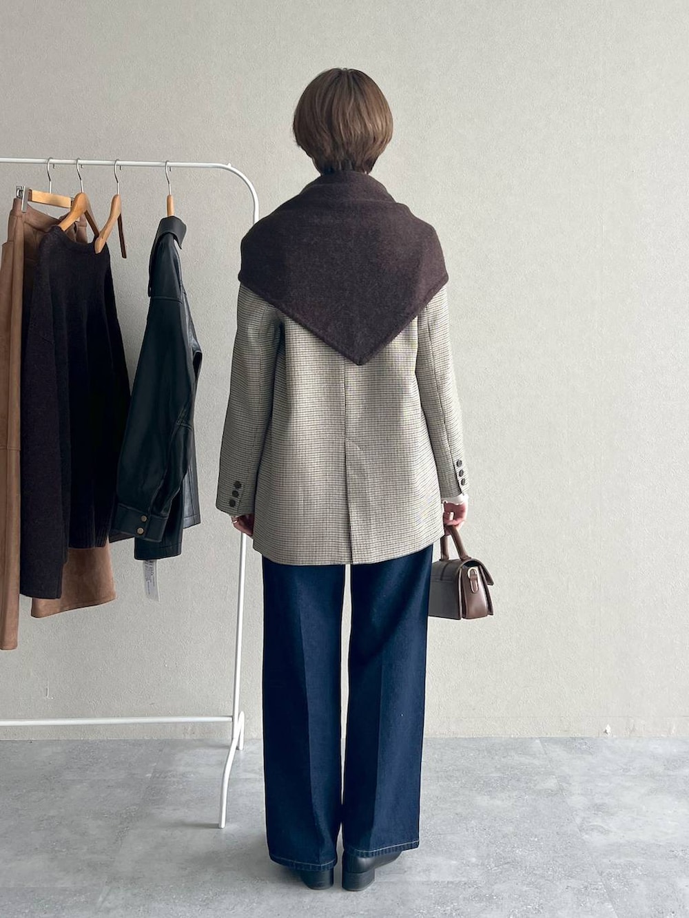 ベージュ系のテーラードジャケット、ブルー系のデニムパンツ、ブラック系のローファーを着用したレディースの秋コーディネートの3枚目の写真