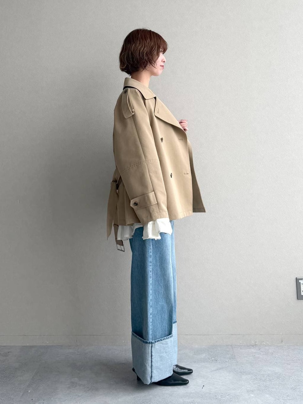 ブラック系のサンダル、ベージュ系のトレンチコート、ブルー系のデニムパンツを着用したレディースの春コーディネートの2枚目の写真