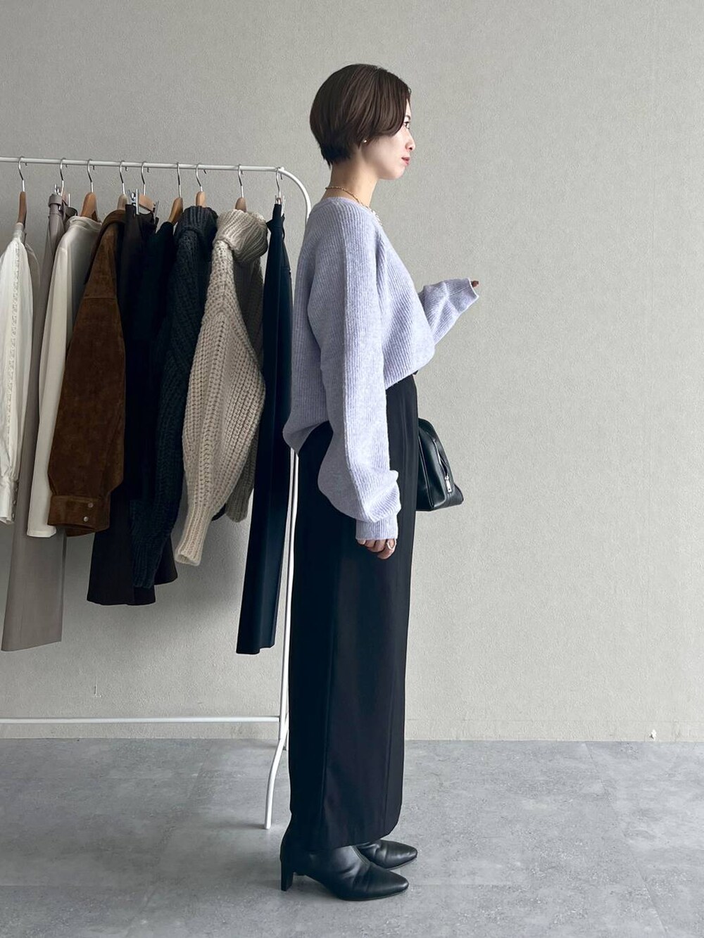 パープル系のニット/セーター、ブラック系のブーツ、ブラック系のトートバッグを着用したレディースの秋コーディネートの2枚目の写真