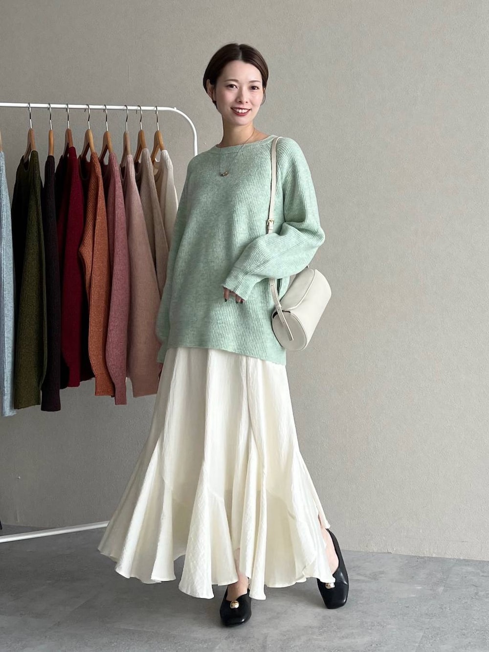 ホワイト系のスカート、ブラック系のブルゾン、ホワイト系のショルダーバッグを着用したレディースの秋コーディネートの4枚目の写真