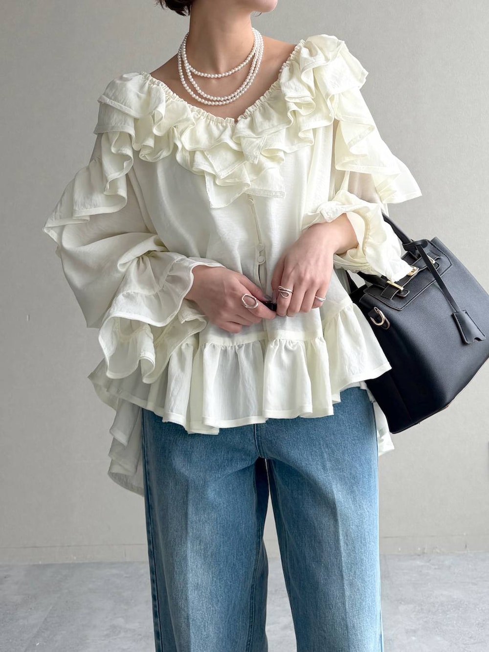 ブラック系のサンダル、ベージュ系のトレンチコート、ブルー系のデニムパンツを着用したレディースの春コーディネートの8枚目の写真