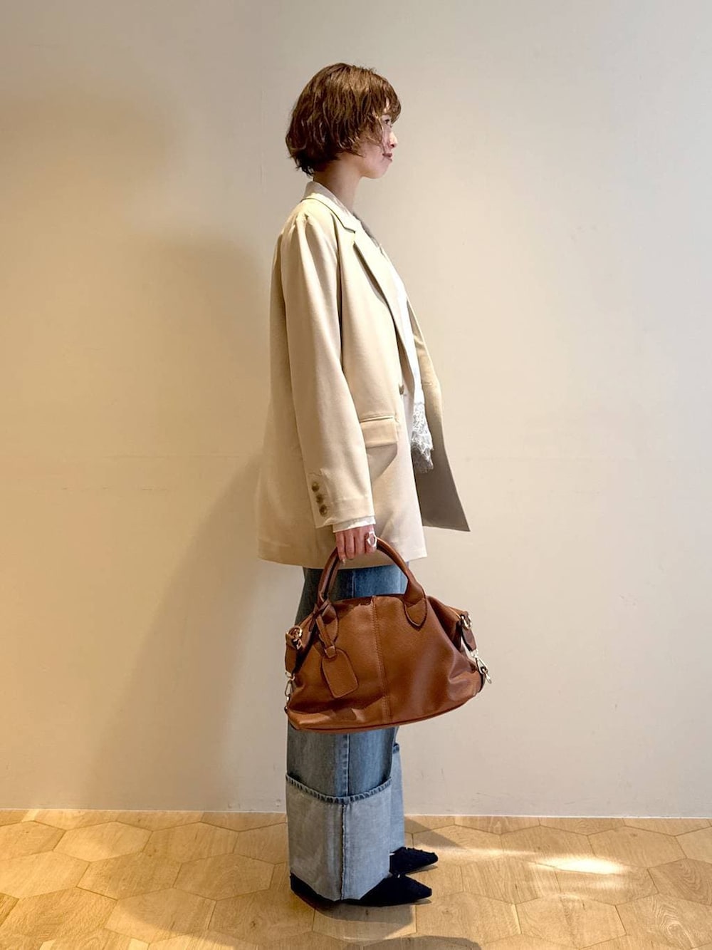 ブラウン系のボストンバッグ、ブルー系のパンプス、ホワイト系のキャミソールを着用したレディースの冬コーディネートの2枚目の写真