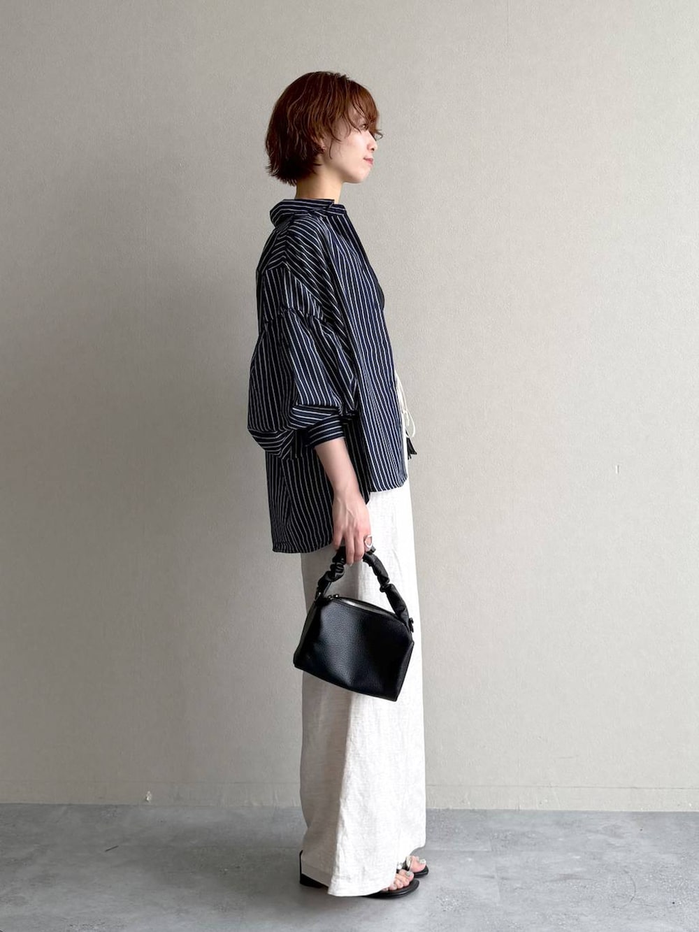 ブラック系のニット/セーター、ベージュ系のその他パンツ、ブラック系のショルダーバッグを着用したレディースの夏コーディネートの2枚目の写真