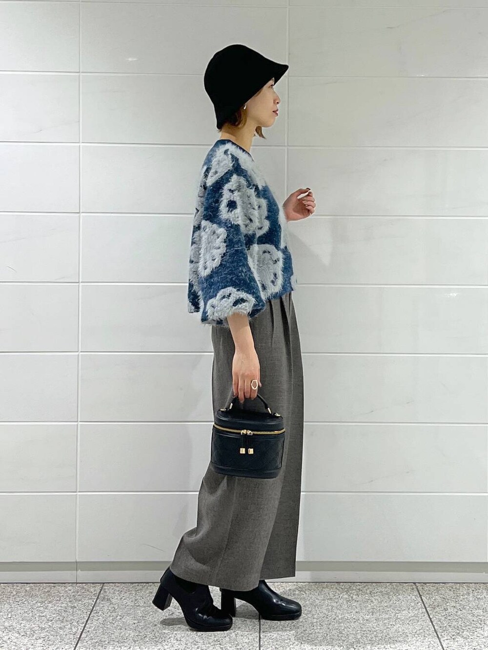 ブルー系のニット/セーター、ブラック系のショルダーバッグ、ブラック系のブーツを着用したレディースの秋コーディネートの3枚目の写真