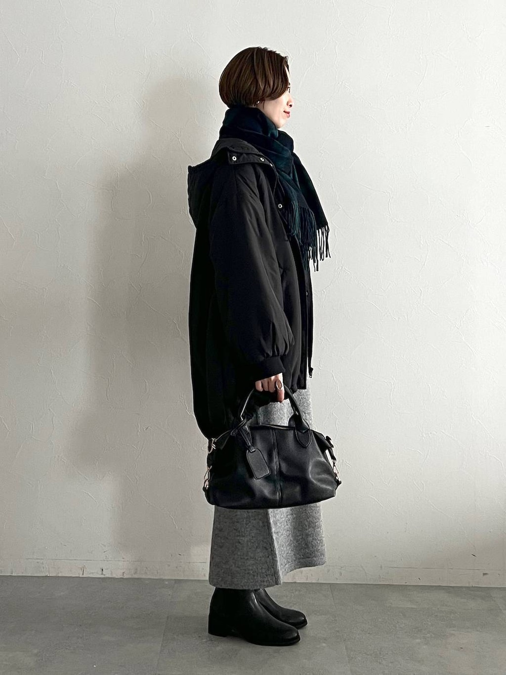 ブラック系のボストンバッグ、ブラック系のブーツ、ブラック系のブルゾンを着用したレディースの冬コーディネートの2枚目の写真