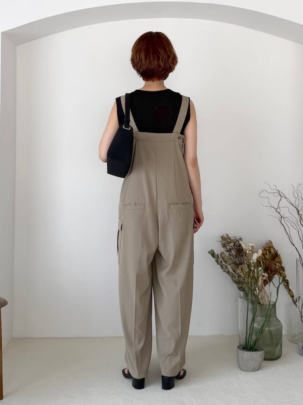ブラック系のニット/セーター、ベージュ系のサロペット/オーバーオール、ブラック系のサンダルを着用したレディースの夏コーディネートの3枚目の写真