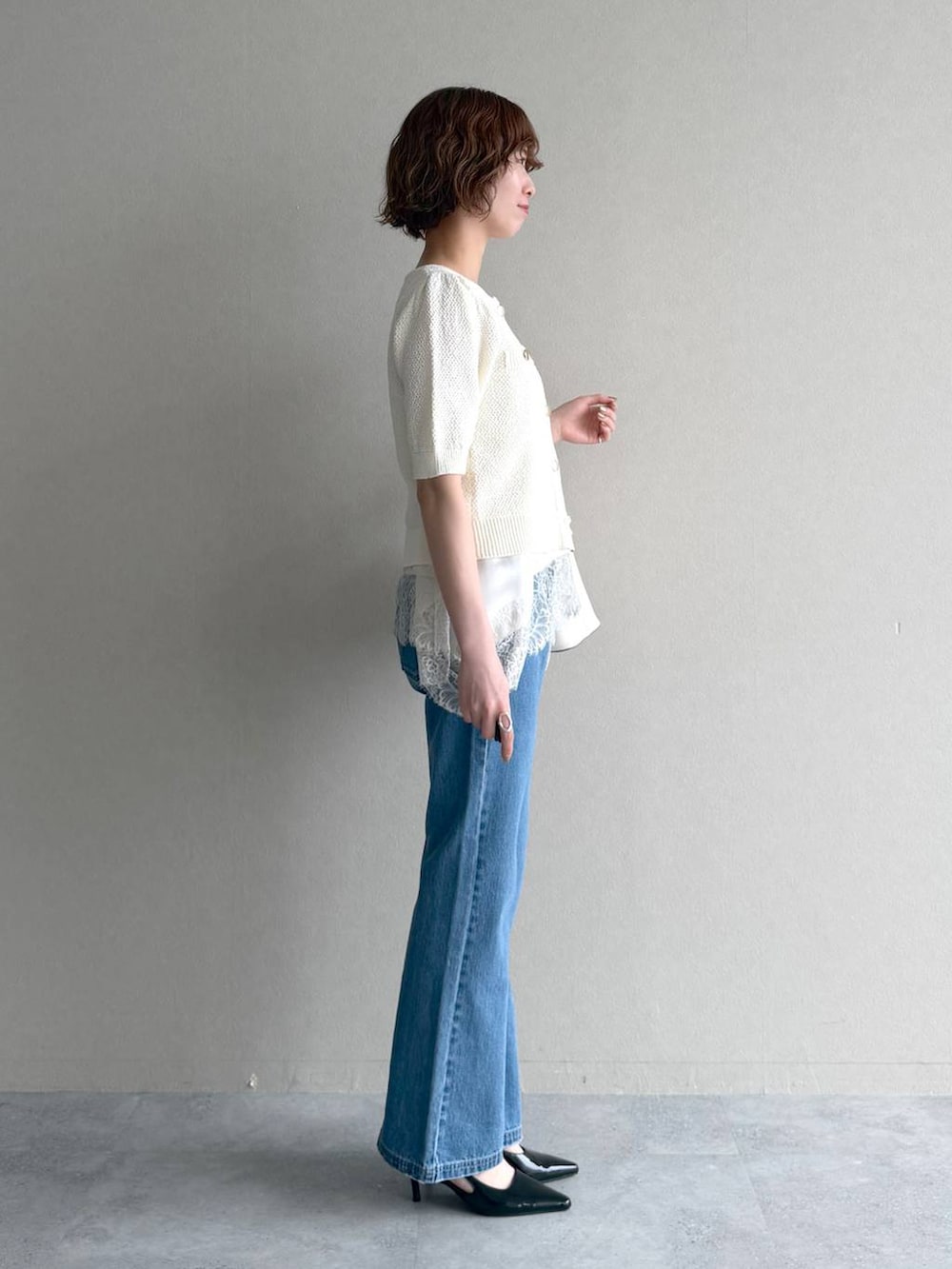 ホワイト系のカーディガン/ボレロ、ブルー系のデニムパンツ、ブラック系のサンダルを着用したレディースの春コーディネートの2枚目の写真