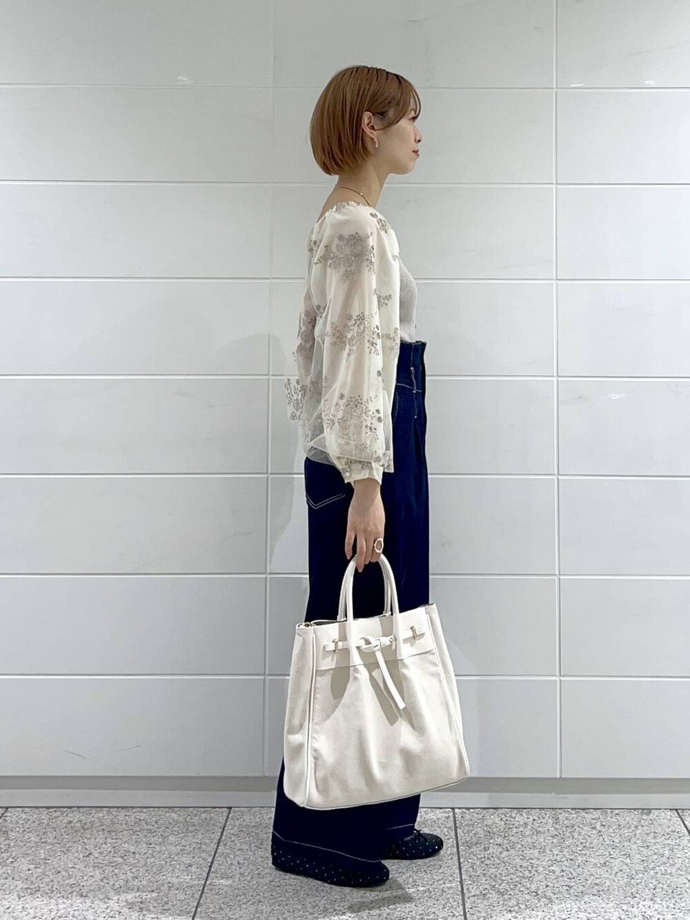 ホワイト系のトートバッグ、ブラック系のバレエシューズ、ブルー系のデニムパンツを着用したレディースの春コーディネートの2枚目の写真