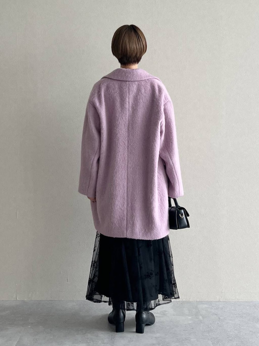 ブラック系のワンピース、パープル系のチェスターコート、ブラック系のブーツを着用したレディースの秋コーディネートの3枚目の写真