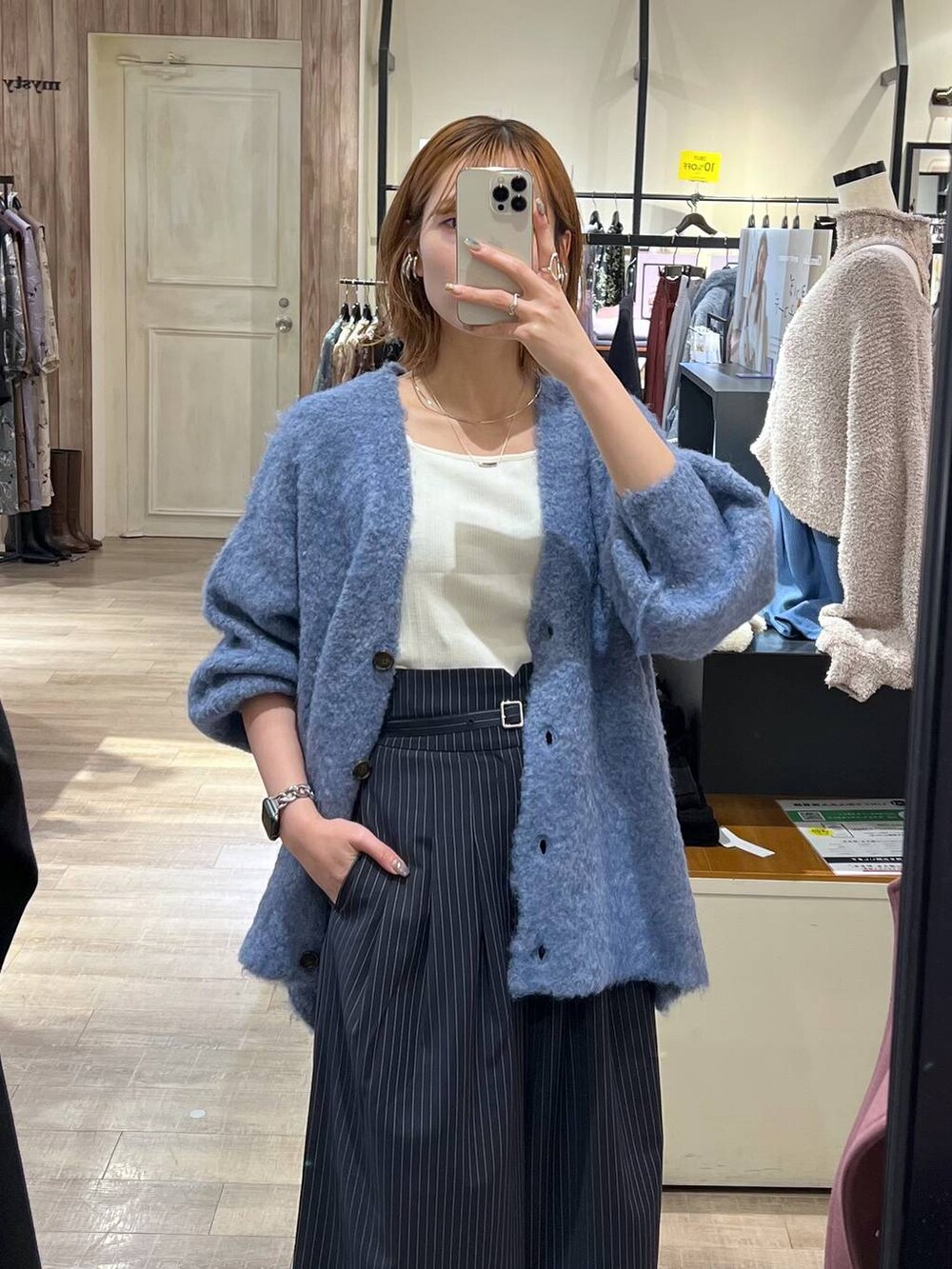 ホワイト系のタンクトップ、ホワイト系のハンドバッグ、ブラック系のブーツを着用したレディースの秋コーディネートの4枚目の写真