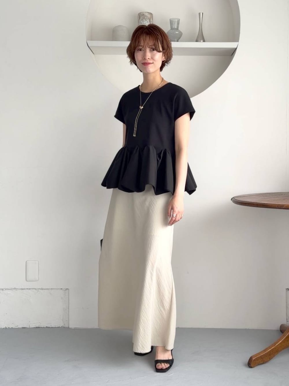ブラック系のサンダル、ベージュ系のスカート、ブラック系のショルダーバッグを着用したレディースの夏コーディネートの2枚目の写真