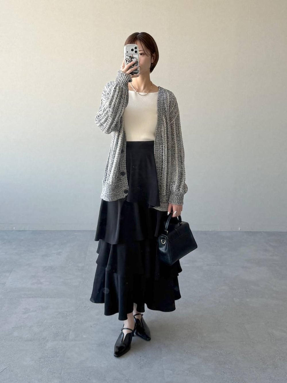 ブラック系のショルダーバッグ、ブラック系のサンダル、ホワイト系のニット/セーターを着用したレディースの冬コーディネートの5枚目の写真