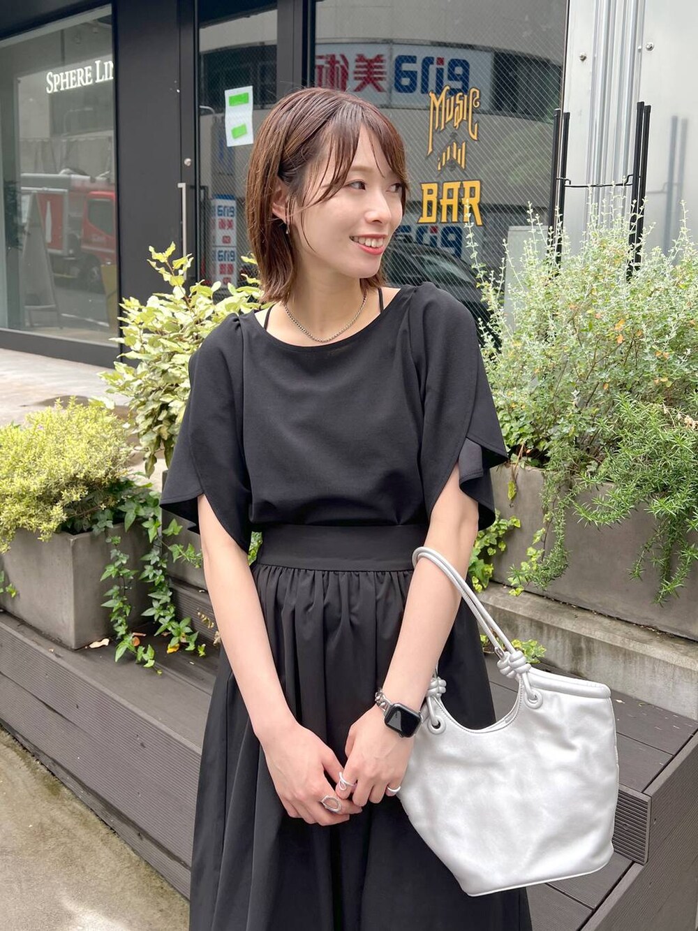 シルバー系のハンドバッグ、ブラック系のサンダル、ブラック系のスカートを着用したレディースの春コーディネートの3枚目の写真
