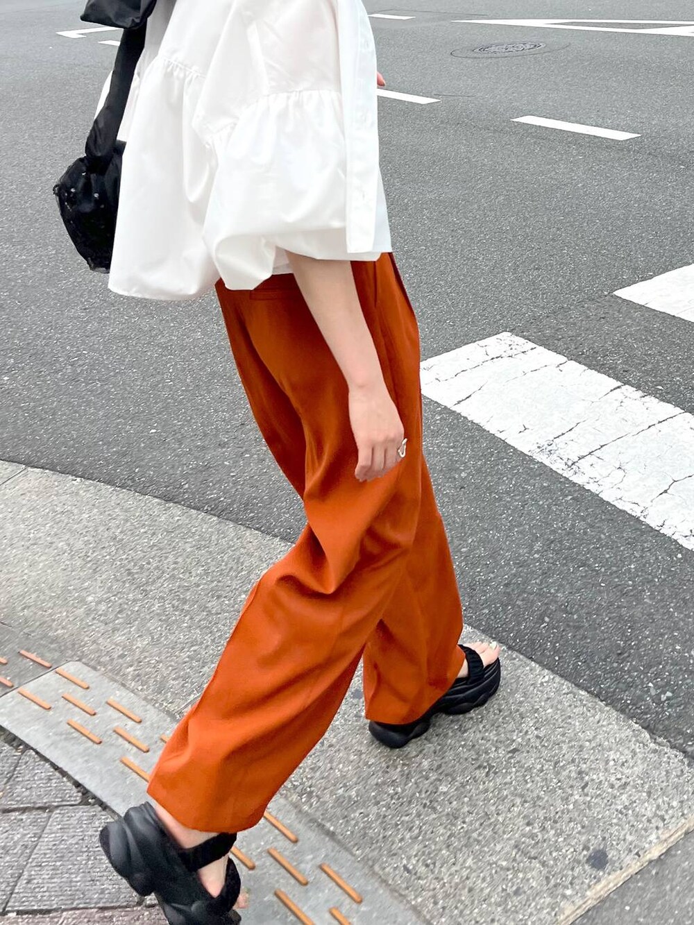 ブラック系のショルダーバッグ、ホワイト系のシャツ/ブラウス、オレンジ系のスラックスを着用したレディースの秋コーディネートの5枚目の写真