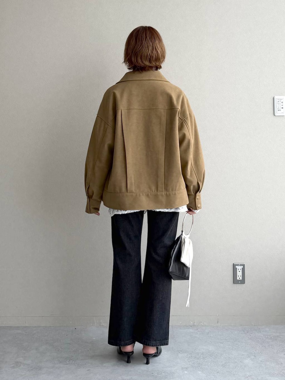 ブラック系のデニムパンツ、ブラック系のサンダル、ブラウン系のブルゾンを着用したレディースの冬コーディネートの3枚目の写真