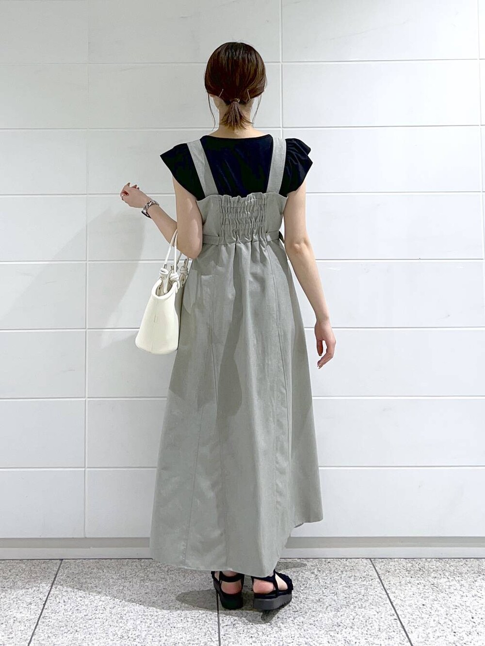 ブラック系のサンダル、ホワイト系のハンドバッグ、ブラック系のTシャツ/カットソーを着用したレディースの春コーディネートの3枚目の写真