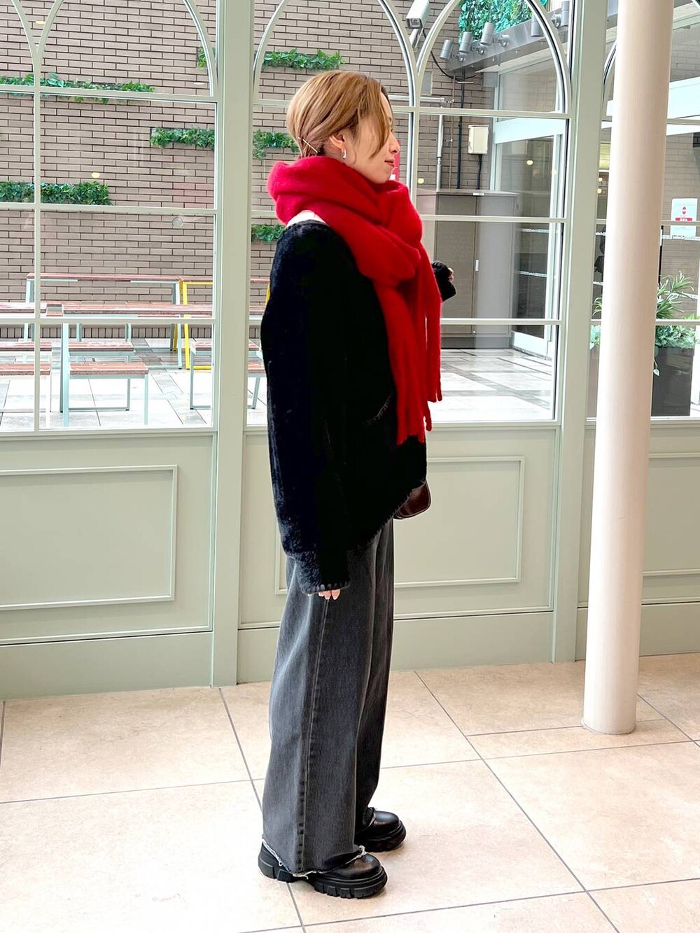 ブラック系のデニムパンツ、ブラック系のブーツ、ブラウン系のハンドバッグを着用したレディースの秋コーディネートの2枚目の写真