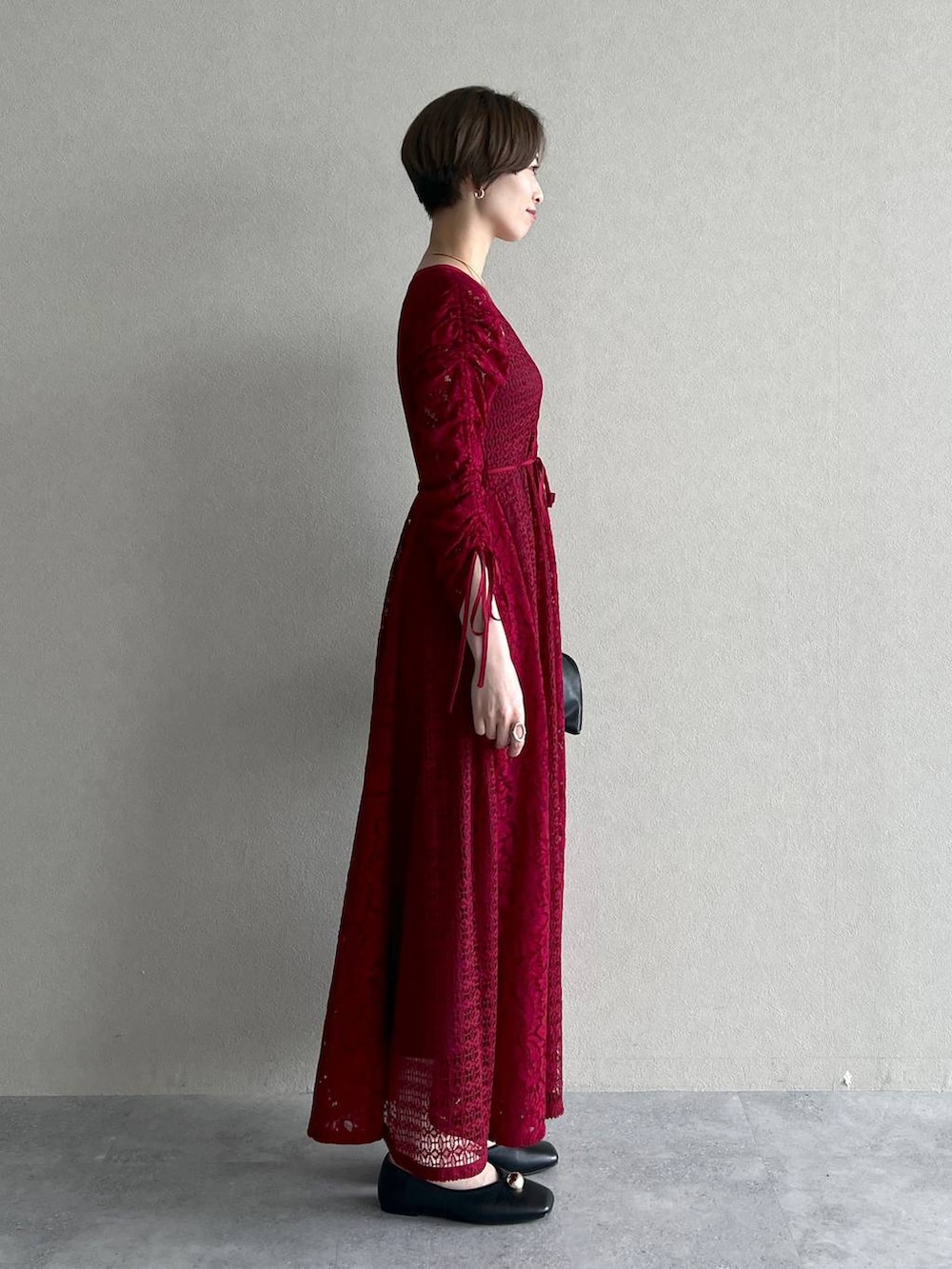 ブラック系のブルゾン、ブラック系のハンドバッグ、レッド系のワンピースを着用したレディースの秋コーディネートの6枚目の写真