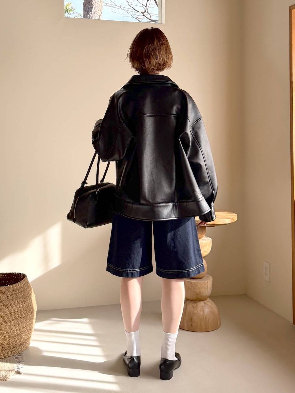 ブラック系のハンドバッグ、ブラック系のローファー、ブラック系のブルゾンを着用したレディースの冬コーディネートの3枚目の写真