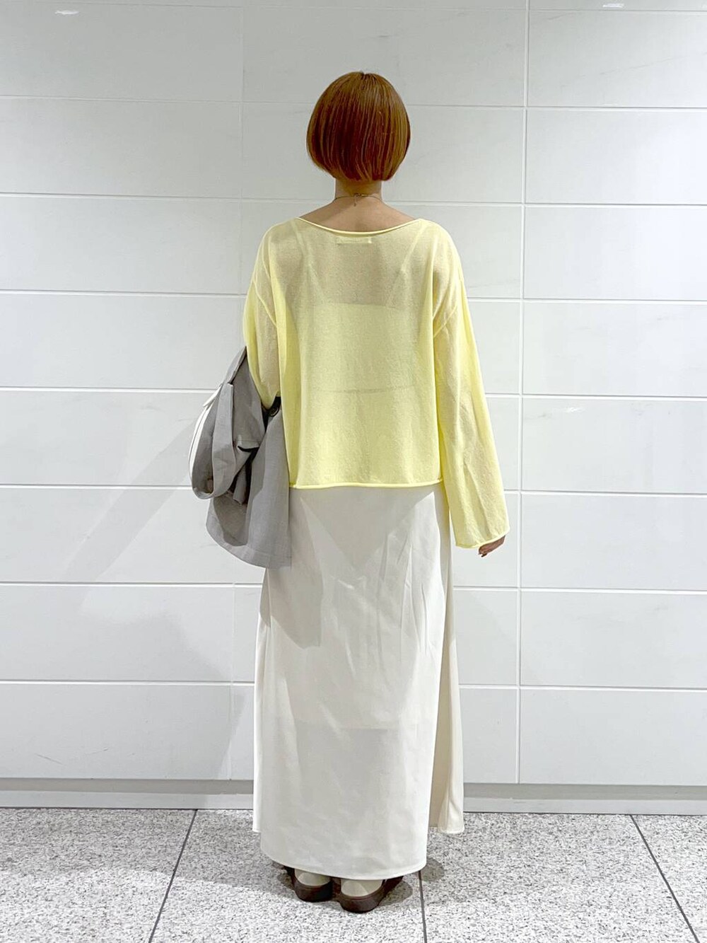 イエロー系のニット/セーター、グレー系のテーラードジャケット、ホワイト系のスカートを着用したレディースの春コーディネートの6枚目の写真